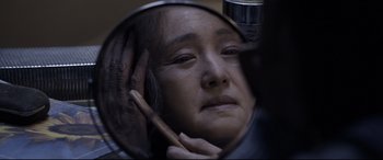 Movie still from “Coming Home” (2014), directed by Yimou Zhang – An older woman looking in a mirror with her hand on her head; Close Up shot, Over the shoulder angle