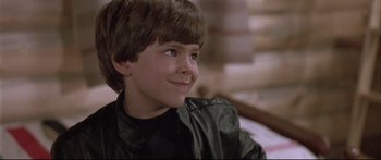 Movie still from “Communion” (1989), directed by Philippe Mora – A young boy wearing a leather jacket looking to his left; Close Up shot, Low angle