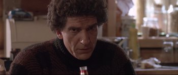 Movie still from “Communion” (1989), directed by Philippe Mora – A person holding a bottle of beer; Close Up shot, Low angle