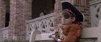 Movie still from “Communion” (1989), directed by Philippe Mora – A young boy dressed up as a pirate sitting on a bench; Medium shot, Low angle