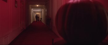 Movie still from “Communion” (1989), directed by Philippe Mora – Two people walking down a long red hallway; Wide shot, Low angle