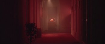 Movie still from “Communion” (1989), directed by Philippe Mora – A room with a red light and a pumpkin in the middle of the room; Wide shot, High angle