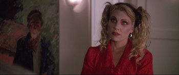 Movie still from “Communion” (1989), directed by Philippe Mora – A woman in a red dress is looking to her left; Close Up shot, Over the shoulder angle