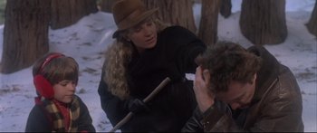 Movie still from “Communion” (1989), directed by Philippe Mora – A woman in a brown hat holding two sticks and talking to a man in a brown hat; Medium shot, Over the shoulder angle
