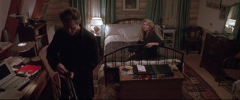 Movie still from “Communion” (1989), directed by Philippe Mora – A woman sitting on a bed next to a man in a room; Wide shot, High angle