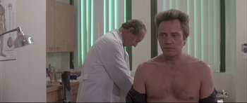 Movie still from “Communion” (1989), directed by Philippe Mora – A man is getting his arm examined by a doctor; Medium shot, Over the shoulder angle
