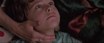 Movie still from “Communion” (1989), directed by Philippe Mora – A child laying on the ground; Close Up shot, Overhead angle
