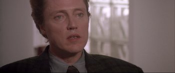 Movie still from “Communion” (1989), directed by Philippe Mora – A person wearing a suit and tie; Close Up shot, Low angle