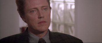 Movie still from “Communion” (1989), directed by Philippe Mora – A person wearing a suit and tie; Close Up shot, Over the shoulder angle