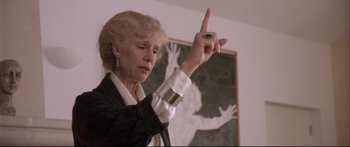 Movie still from “Communion” (1989), directed by Philippe Mora – An older woman is pointing to a painting; Close Up shot, Low angle