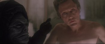 Movie still from “Communion” (1989), directed by Philippe Mora – A man is looking into a mirror while holding a knife; Close Up shot, Over the shoulder angle