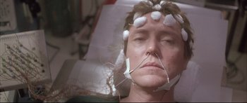 Movie still from “Communion” (1989), directed by Philippe Mora – A man with wires attached to his head and face; Close Up shot, Overhead angle