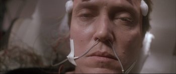 Movie still from “Communion” (1989), directed by Philippe Mora – A man with a pair of wires attached to his ears; Close Up shot, High angle