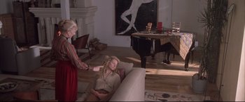Movie still from “Communion” (1989), directed by Philippe Mora – Two women in a living room with a piano in the background; Wide shot, High angle