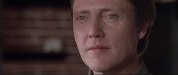 Movie still from “Communion” (1989), directed by Philippe Mora – A man's face with a brick wall in the background; Close Up shot, Low angle