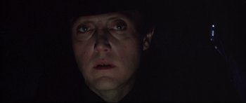 Movie still from “Communion” (1989), directed by Philippe Mora – A man in a black shirt and a black hat; Close Up shot, Low angle
