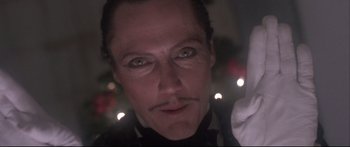 Movie still from “Communion” (1989), directed by Philippe Mora – A person wearing a suit and tie; Close Up shot, Low angle