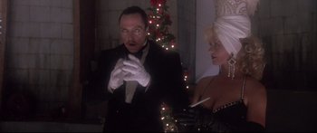 Movie still from “Communion” (1989), directed by Philippe Mora – A man in a tuxedo and a woman in a black dress and white gloves; Medium shot, Low angle