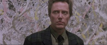 Movie still from “Communion” (1989), directed by Philippe Mora – A person wearing a suit and tie; Close Up shot, Low angle