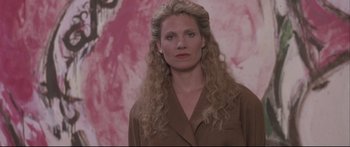Movie still from “Communion” (1989), directed by Philippe Mora – A woman with long blonde curly hair wearing a brown jacket; Close Up shot, Low angle