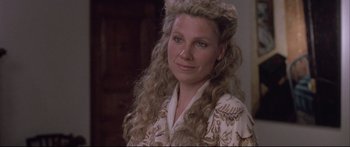 Movie still from “Communion” (1989), directed by Philippe Mora – A person with long curly blonde hair; Close Up shot, Over the shoulder angle