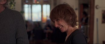 Movie still from “Compartment Number 6” (2021), directed by Juho Kuosmanen – A person with a smile on their face; Close Up shot, Over the shoulder angle