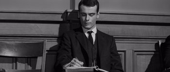 Movie still from “Compulsion” (1959), directed by Richard Fleischer – A man in a suit and tie writing on a notebook; Close Up shot, High angle