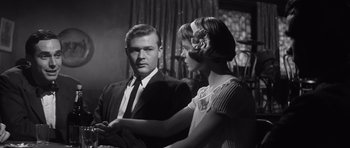 Movie still from “Compulsion” (1959), directed by Richard Fleischer – A man and a woman standing next to each other in a room; Medium shot, Low angle