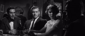 Movie still from “Compulsion” (1959), directed by Richard Fleischer – A man and a woman standing next to each other; Medium shot, Low angle