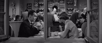 Movie still from “Compulsion” (1959), directed by Richard Fleischer – A man and a woman sitting at a table in a restaurant; Medium shot, High angle