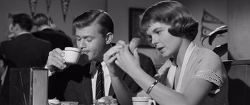 Movie still from “Compulsion” (1959), directed by Richard Fleischer – A man and a woman sitting at a table drinking coffee; Medium shot, Over the shoulder angle