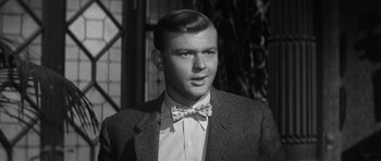 Movie still from “Compulsion” (1959), directed by Richard Fleischer – A man wearing a suit and bow tie; Close Up shot, Over the shoulder angle