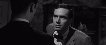 Movie still from “Compulsion” (1959), directed by Richard Fleischer – A black and white photo of a man in a suit and bow tie talking to another man in a suit and bow tie; Close Up shot, Over the shoulder angle