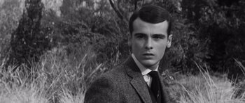 Movie still from “Compulsion” (1959), directed by Richard Fleischer – A man in a suit and tie standing in front of a bush; Close Up shot, Low angle