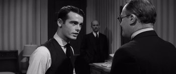 Movie still from “Compulsion” (1959), directed by Richard Fleischer – A man wearing a suit and tie talking to another man wearing a suit and tie; Medium shot, Over the shoulder angle