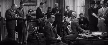 Movie still from “Compulsion” (1959), directed by Richard Fleischer – A black and white photo of a group of men in suits and ties; Medium shot, High angle