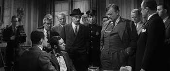 Movie still from “Compulsion” (1959), directed by Richard Fleischer – A black and white photo of a group of men in suits; Medium shot, Over the shoulder angle