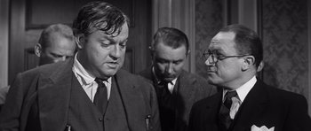 Movie still from “Compulsion” (1959), directed by Richard Fleischer – A group of men standing next to each other in a room; Medium shot, Over the shoulder angle