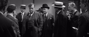 Movie still from “Compulsion” (1959), directed by Richard Fleischer – A group of men standing next to each other wearing hats; Medium shot, Over the shoulder angle