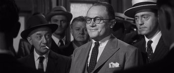 Movie still from “Compulsion” (1959), directed by Richard Fleischer – An older man wearing a suit and tie; Close Up shot, Over the shoulder angle