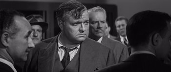 Movie still from “Compulsion” (1959), directed by Richard Fleischer – A black - and - white photo of a man in a suit; Close Up shot, Over the shoulder angle