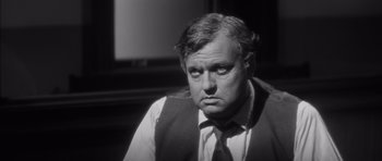 Movie still from “Compulsion” (1959), directed by Richard Fleischer – An older man wearing a suit and tie looking at the camera; Close Up shot, Over the shoulder angle