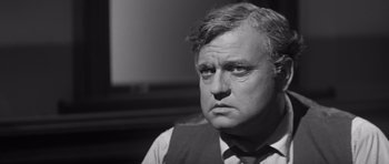 Movie still from “Compulsion” (1959), directed by Richard Fleischer – An older man in a suit and tie looking at the camera; Close Up shot, Over the shoulder angle