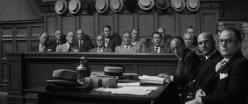 Movie still from “Compulsion” (1959), directed by Richard Fleischer – A black and white photo of a group of men sitting in a courtroom; Medium shot, Low angle