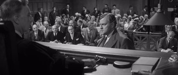 Movie still from “Compulsion” (1959), directed by Richard Fleischer – An old photo of a man in a courtroom; Medium shot, Over the shoulder angle