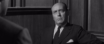 Movie still from “Compulsion” (1959), directed by Richard Fleischer – An old photo of a man in a suit and tie; Close Up shot, Low angle