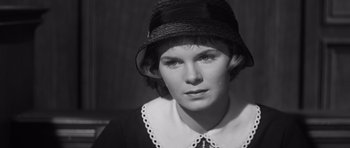 Movie still from “Compulsion” (1959), directed by Richard Fleischer – A woman wearing a black hat and a white collar; Close Up shot, High angle