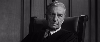 Movie still from “Compulsion” (1959), directed by Richard Fleischer – An older man wearing a black robe and a white tie; Close Up shot, Low angle