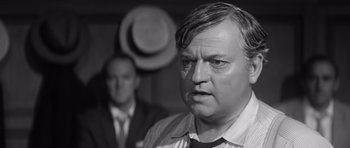 Movie still from “Compulsion” (1959), directed by Richard Fleischer – A black - and - white photo of a man in a suit and tie; Close Up shot, Over the shoulder angle