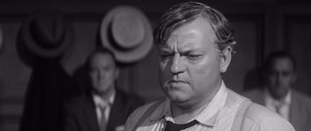 Movie still from “Compulsion” (1959), directed by Richard Fleischer – A black - and - white photo of a man in a suit and tie; Close Up shot, Over the shoulder angle